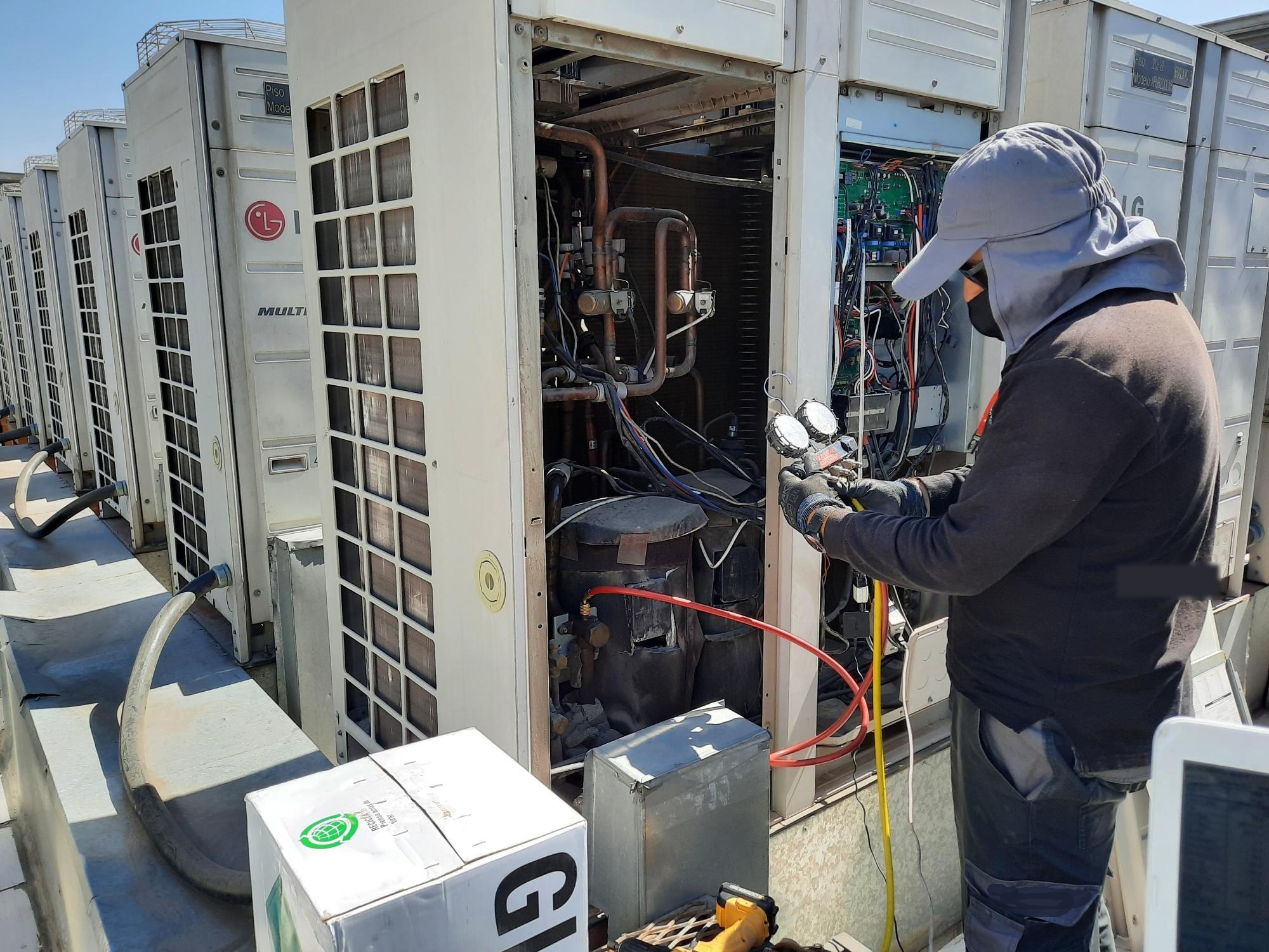 Técnico revisando equipo VRF en azotea con manifold de presiones