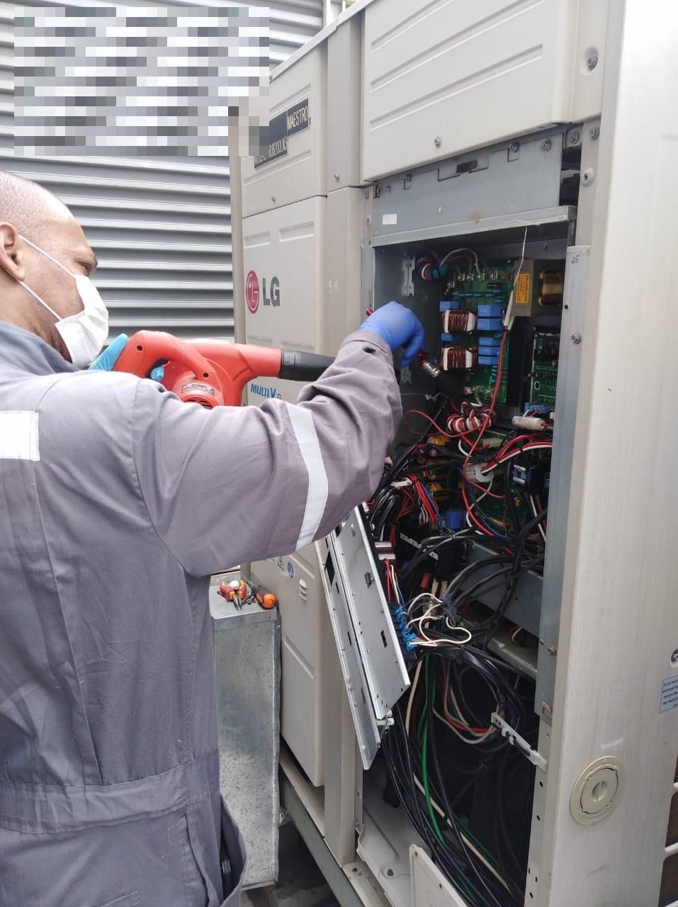 Técnico realizando limpieza de tablero electrónico en equipo LG Multi V