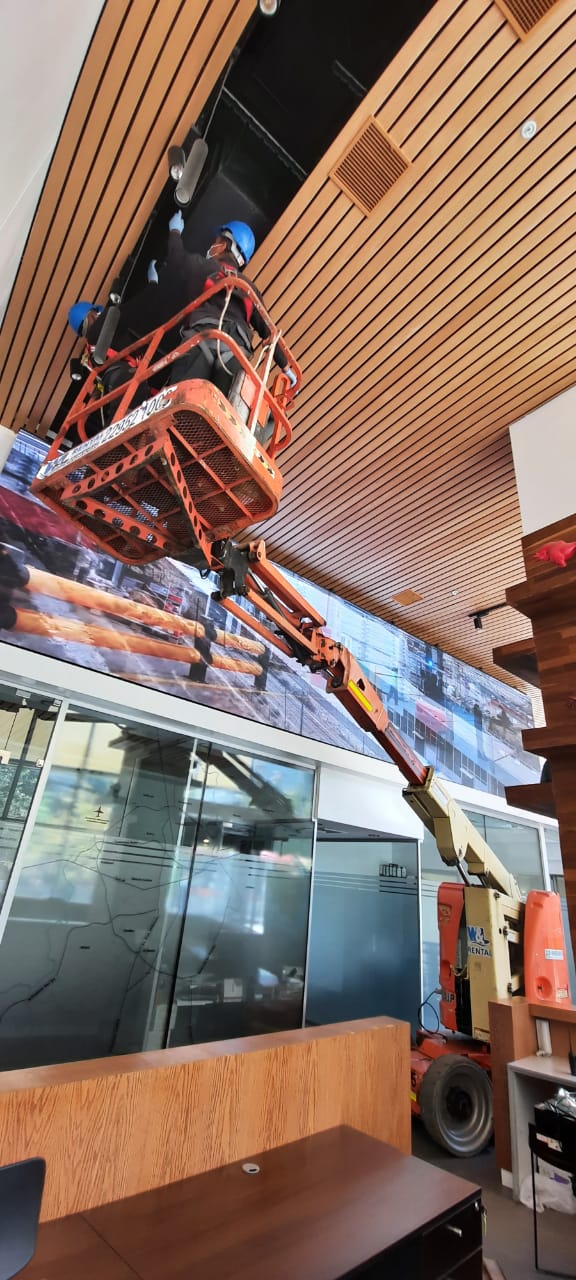 Técnicos en alzahombres realizando instalación en altura en interior